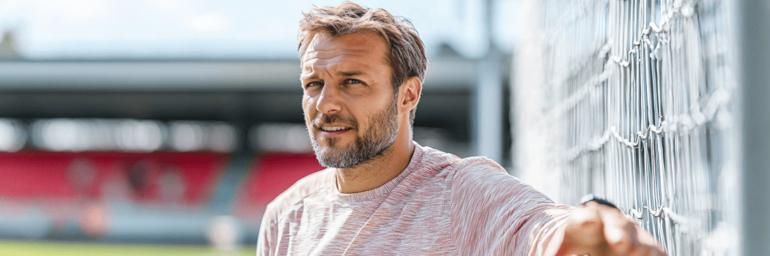 Fußballtrainer lehnt an einem Tor